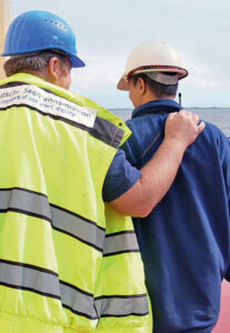 Von hinten: Ein Mitarbeiter der Seemannsmission legt einem Seemann den Arm auf die Schulter - Symbolbild für PSNV (von Diakonie SH)
