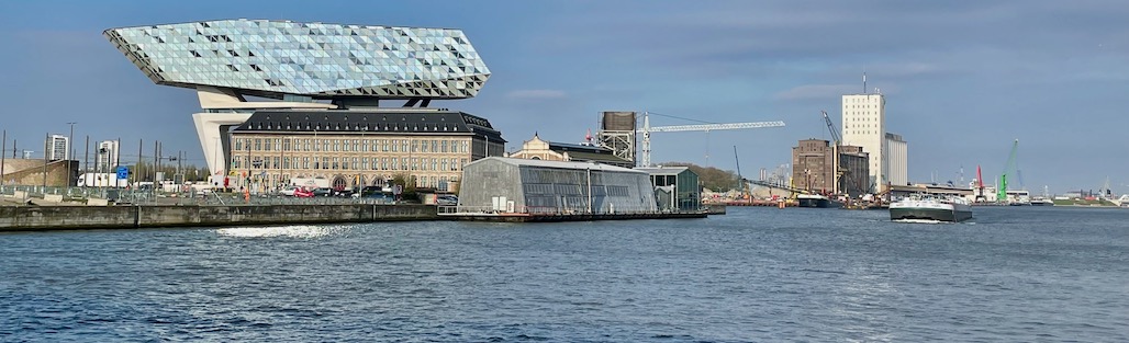 Vorne das blaue Wasser des Hafens, dahinter das Gebäude der Hafenverwaltung von Antwerpen