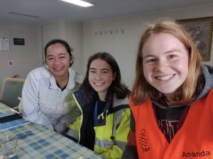 Freiwillige treffen glückliche Seefrau Links die junge Seefrau im weißem Overall, danben die beiden Freiwilligen in gelber und orangener Sicherheitskleidung