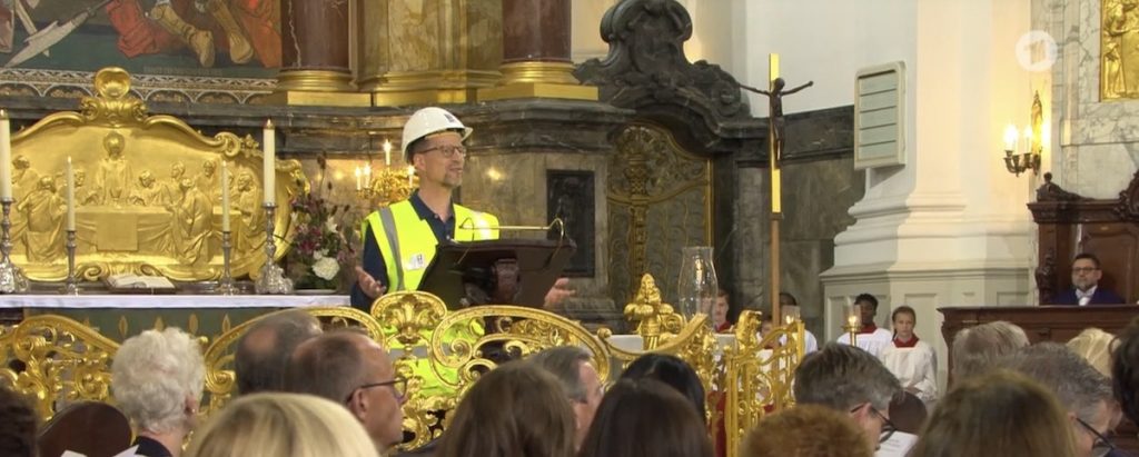 Generalsekretär Matthias Ristau am Rednerpult im Michel. Er trägt den weißen Helm mit Logo der Seemannsmission und eine gelbe Leuchtweste. Vorne sind die Köpfe der Politiker von schräg hinten zu sehen