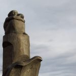 Die Aufnahme zeigt den oberen Teil des Mahnmals Madonna der Seefahrt in der Abendsonne. Deutlich zu erkennen ist die Darstellung einer Frau, die hingekauert die Elbe hinunterblickt