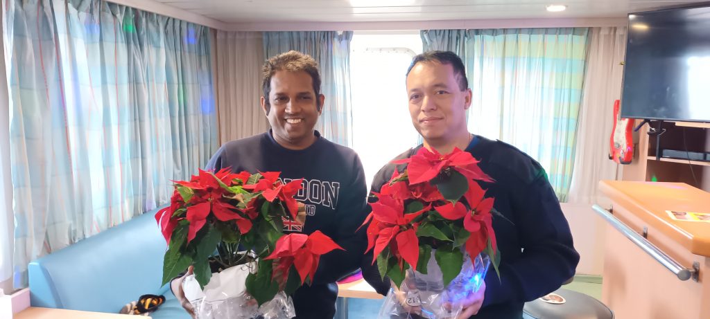 Zwei Seemänner halten Weihnachtssterne in der Hand und lächeln