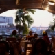 Das Foto zeigt eine Abendstimmung im Restaurant des Seemannhotels Foyer du Marin. Man sieht die Silouette einer Familie, die mit Blick auf den Hafen zu Abend isst. Auch zwei Palmen sind zu sehen. Foto: Klaus Bammann