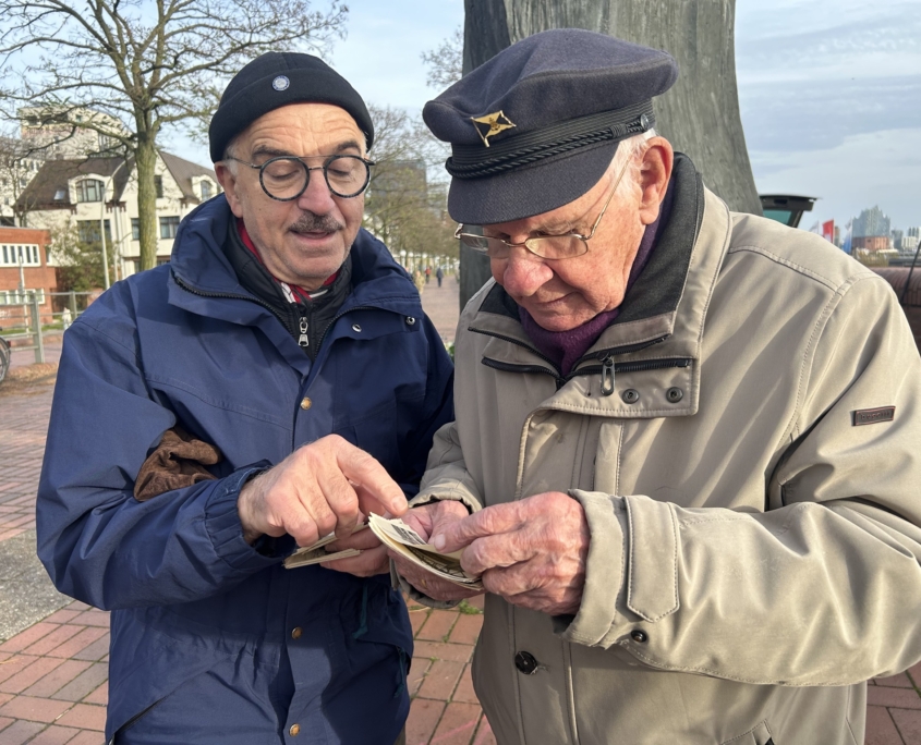 Zwei Seemänner am Altonaer Fischmarkt in Hamburg. Sie schauten sich nach der Gedenkfeier an der Madonna der Seefahrt Schwarz-weiß-Fotos aus den 60er Jahren an.