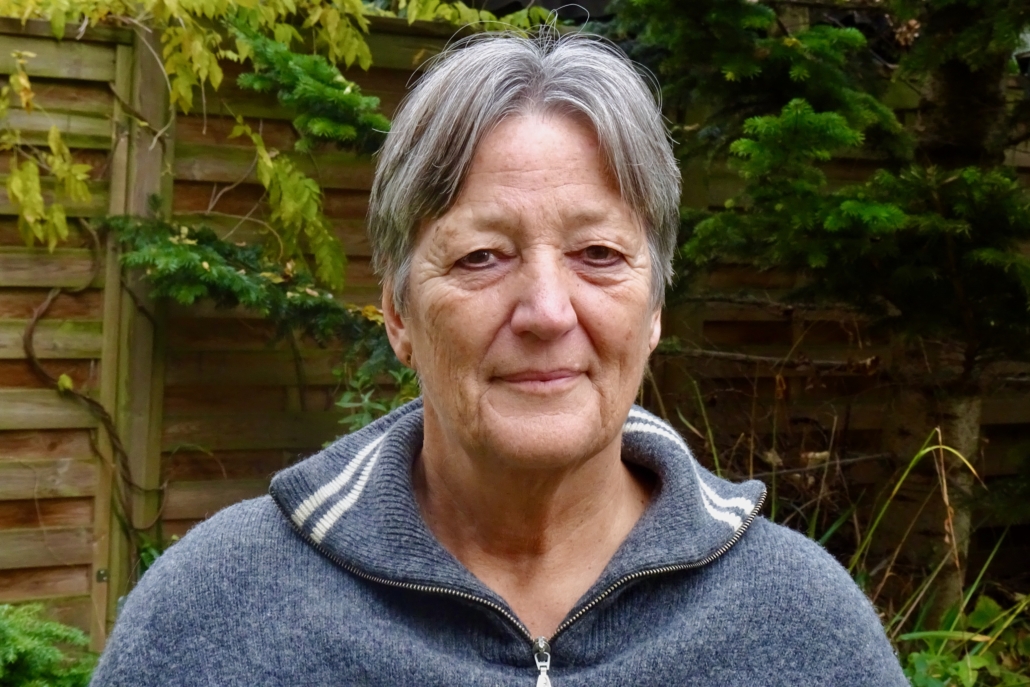 Das Foto zeigt Jenny Sarrazin, die ehrenamtlich bei der Deutschen Seemannsmission in Cuxhaven aktiv ist. Im Bild ist sie in einem Garten zu sehen. Sie trägt einen grauen Woll-Troyer, der zwei weiße Streifen am Kragen hat.