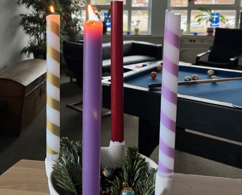 Bunt ist der Adventskranz der Seemannsmission Lübeck. Jede Kerze hat eine andere Farbe, von gold-gestreift, über lila, bordeauxrot bishin zu lila-weiß-gestreift sind die langen Stabkerzen im Seemannsclub vielfältig wie die Menschen, die dort ein- und ausgehen.