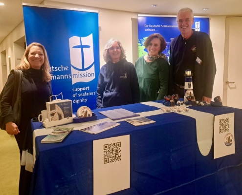 Das Foto zeigt eine Art Messestand hinter dem die Tiefseeforscherin Anje Boetius (links), daneben die Leiterin des Seemannsclubs Duckdalben, Eliane Lafendt steht. Rechts von Lafendt steht die Präsidentin der Deutschen Seemannsmission Dr. Clara Schlaich.