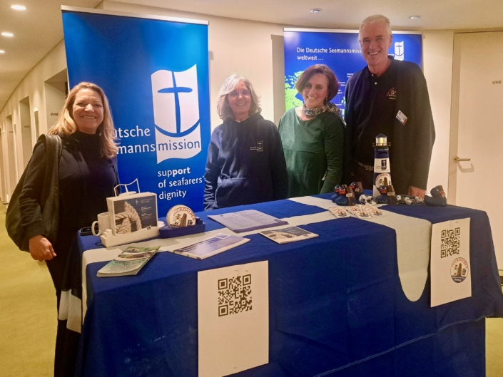 Das Foto zeigt eine Art Messestand hinter dem die Tiefseeforscherin Anje Boetius (links), daneben die Leiterin des Seemannsclubs Duckdalben, Eliane Lafendt steht. Rechts von Lafendt steht die Präsidentin der Deutschen Seemannsmission Dr. Clara Schlaich.