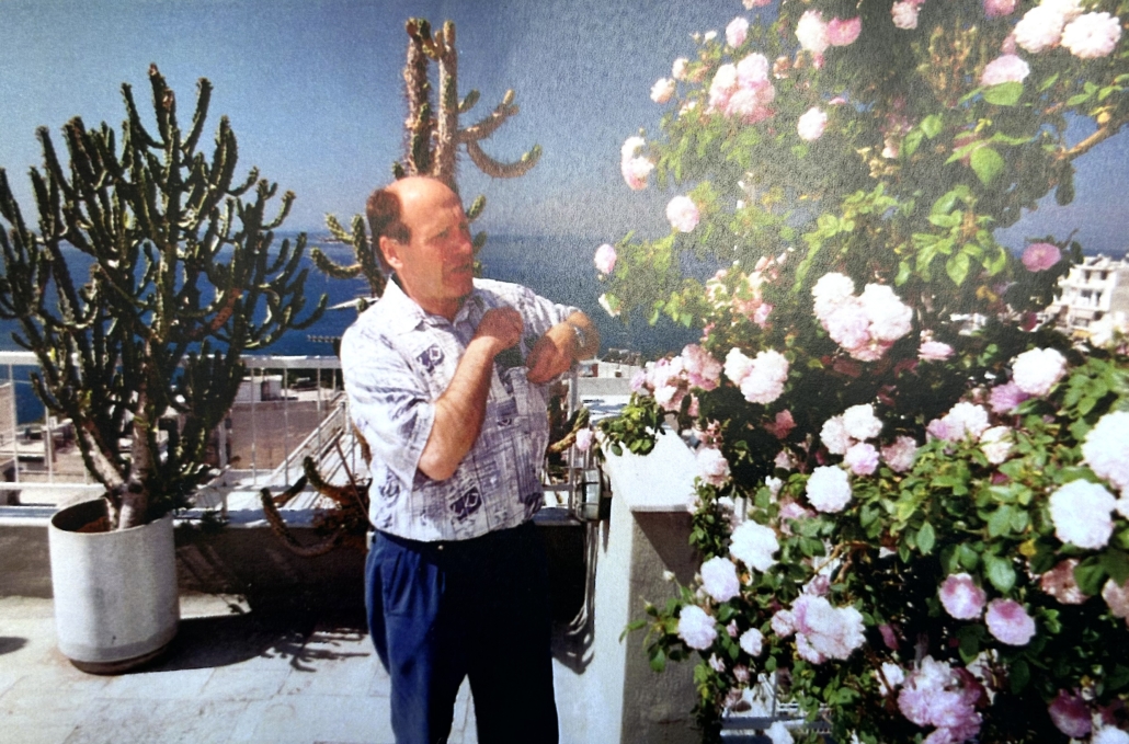 Das Foto zeigt den ehemaligen Seemannsdiakon Walter Bott auf der Terrasse des Seemannsheims in Piräus. Bott war ein begnadeter Gärtner, züchtete Rosen und ernetete jedes Jahr kiloweise Tomaten. Das Foto ist Ende der 1980er Jahre entstanden und zeitgt ihn in einem kurärmeligen weißen Hemd und langer dunkler Hose. Die Sonne scheint, im Hintergrund sind Kakteen zu sehen, die in Töpfen ebenfalls auf der Terrasse stehen.