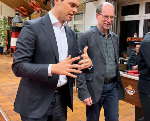 CDU-Politiker Christoph Ploß (li.) und Matthias Ristau, Generalsekretär der Deutschen Seemannsmission e.V., beim Besuch im Seemannsclub Duckdalben. Hier durchqueren sie gerade ein Zimmer, in dem Seeleute Billard spielen und ihre Freizeit genießen.