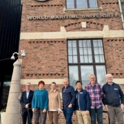 Das Foto zeigt die Akteure des neuen Netzwerks rund um maritime PSNV. Das bedeutet Psychosoziale Notfallversorgung. Vier Akteure kümmern sich im westeuropäischen Raum um Seeleute, die World Maritime University (WMU) im schwedischen Malmö ist der fünfte Kooperationspartner. Die sieben Menschen stehen vor dem Gebäude der WMU in Malmö.