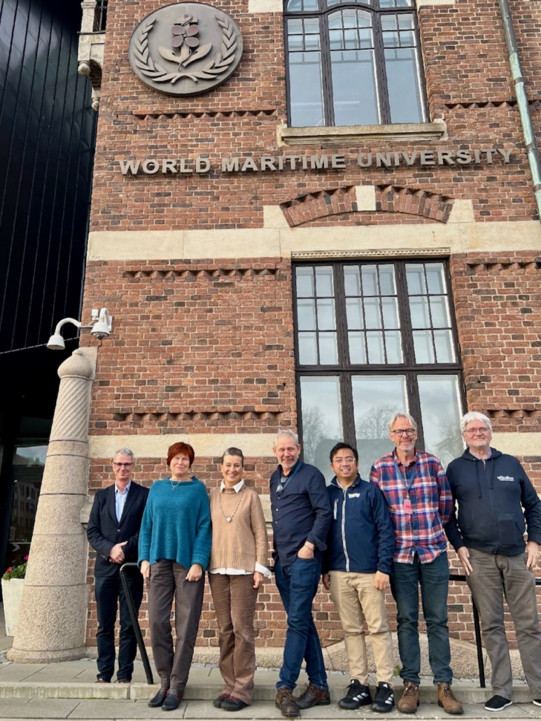 Das Foto zeigt die Akteure des neuen Netzwerks rund um maritime PSNV. Das bedeutet Psychosoziale Notfallversorgung. Vier Akteure kümmern sich im westeuropäischen Raum um Seeleute, die World Maritime University (WMU) im schwedischen Malmö ist der fünfte Kooperationspartner. Die sieben Menschen stehen vor dem Gebäude der WMU in Malmö.